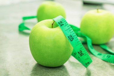 Measure tape and green apple on stone background close up, healthy food concept