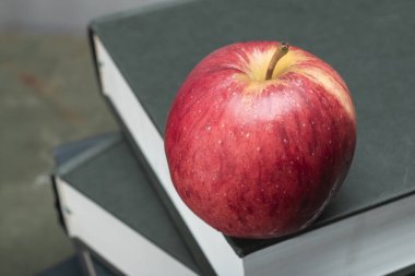 Apple on stack of book on green wood table study, top view.