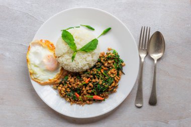 Stir fried basil with minced pork and fried egg on white table close up, top view, Thai food concept.