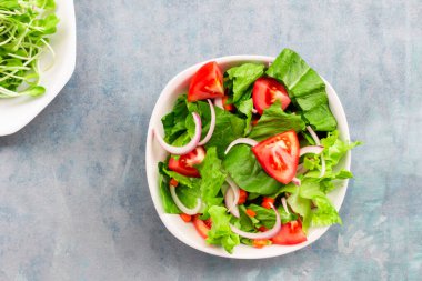 Marul salatasında domates var. Mavi ahşap arka planda, üst tarafta, sağlıklı sebze konsepti..