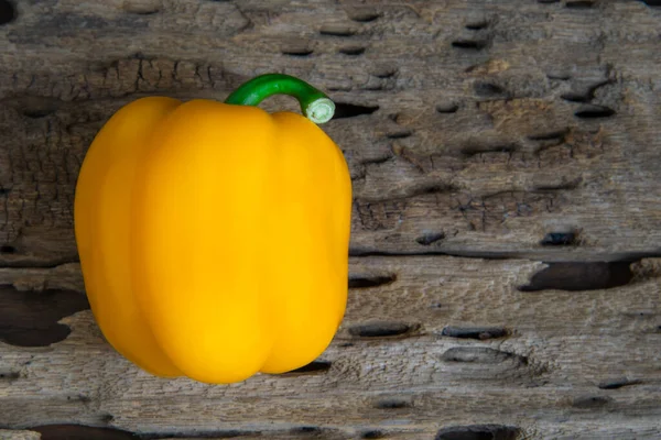 Yellow sweet pepper on wood background close up, top view, healthy food concept.