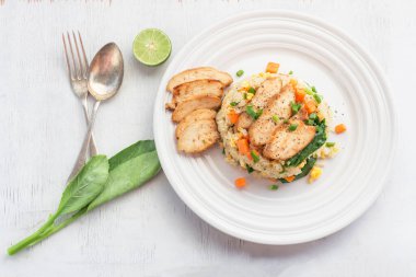 Fried rice dish with chicken breast has vegetable kale carrot in white plate isolated on wood background close up, top view, healthy food and drink concept.