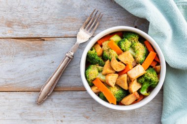 Stir fried chicken add broccoli carrot in bowl on wood background, top view, food and drink concept.