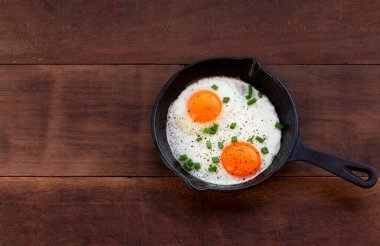 Tavada kızartılmış yumurta, ahşap arka planda izole. Yakın plan, üst manzara, kahvaltı yemeği konsepti..