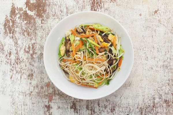 Stir fry chow mein Chinese noodles add bean sprout mushroom cabbage carrot in plate on wood background, top view, healthy vegetarian food concept