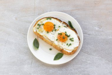 Fried egg on bread slice in plate isolated on white wood background close up, top view, breakfast food and drink concept.