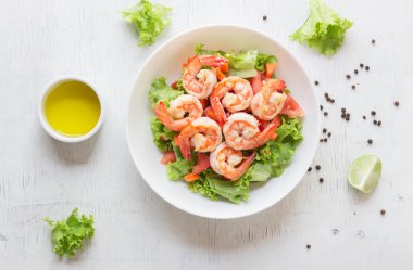 Shrimp salad lettuce carrot tomato in bowl on wood background top view, healthy food concept.