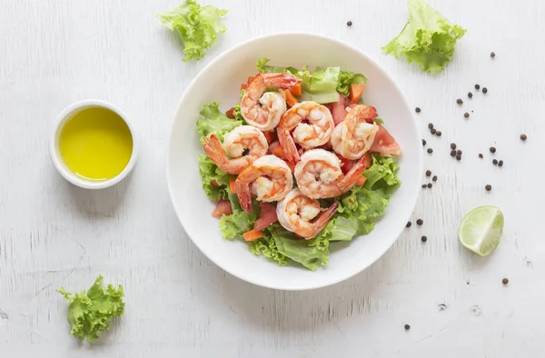 Shrimp salad lettuce carrot tomato in bowl on wood background top view, healthy food concept.