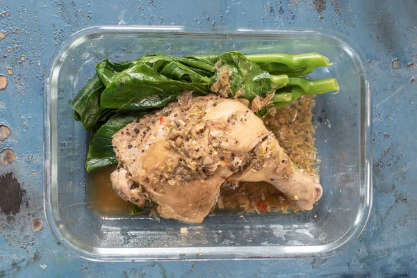 Steamed chicken with herbs in lunch box on blue wood background top view, healthy food concept.