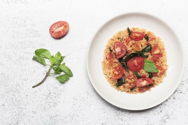 Domatesli pilavın kasesinde fesleğen var. Arka planda, üst tarafta, sağlıklı yiyecek konseptinde..