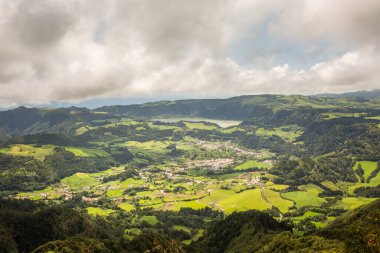 Azores, Sao Miguel Adası 'ndaki Miradouro do Salto do Cavalo' dan çekilen yemyeşil Furnas Vadisi 'nin çarpıcı panoramik görüntüsü. Bu nefes kesici manzara dramatik bir gökyüzü altında yuvarlanan tepeleri, volkanik arazileri ve yama alanlarını içerir. # El #