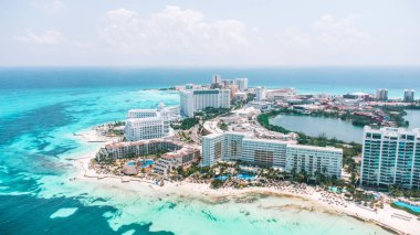 Arkasında şehir olan güzel bir sahil. Şehir yüksek binalarla dolu ve plaj insanlarla dolu. Gökyüzü açık. Cancun Otel bölgesinin havadan görünüşü, Quintana Roo Mexico 