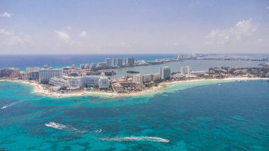 Arka planda bir şehir olan güzel mavi bir okyanus. Şehir beyaz binalarla dolu ve su sakin. Cancun Otel bölgesinin havadan görünüşü, Quintana Roo Mexico 