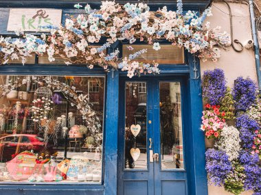 Kilkenny Ireland, Temmuz 2023. Önünde çiçek aranjmanı olan Blue mağazası. Çiçekler pembe ve mavi. Mağaza vitrininde mavi bir tente ve üzerinde 