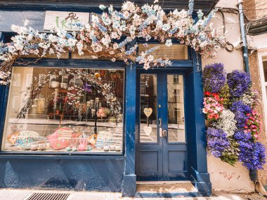 Kilkenny Ireland, Temmuz 2023 Mavi mağaza önü mavi bir kapı ve üzerinde kalp olan bir pencere. Mağaza vitrini çiçeklerle süslenmiş ve İrlanda, Kilkenny 'de mavi bir tentesi var.