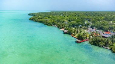 Bacalar, Mexico, Quintana Roo, Beautiful blue ocean with a green shoreline and a red dock. The water is calm and the sky is clear