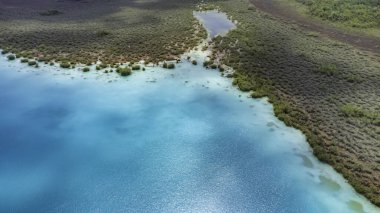 Bacalar, Mexico, Quintana Roo, Beautiful blue ocean with a green shoreline. The water is calm and clear. The sky is blue and there are no clouds