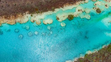 Bacalar, Mexico, Quintana Roo, Blue body of water with a greenish tint. The water is calm and clear. The sky is blue and there are no clouds