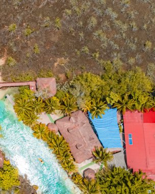 Bacalar, Mexico, Quintana Roo, Beach with a red roof and a blue canopy. The canopy is on the right side of the beach