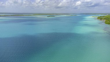 Bacalar, Mexico, Quintana Roo, Beautiful blue ocean with a few islands in the distance. The water is calm and peaceful. The sky is clear and blue, with no clouds in sight. The scene is serene and relaxing
