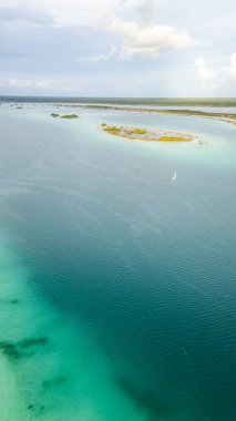 Bacalar, Mexico, Quintana Roo, The ocean is calm and blue, with a small island in the distance. The sky is clear and the sun is shining