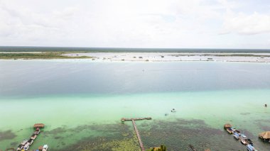 Bacalar, Meksika, Quintana Roo, üzerinde birkaç tekne yüzen güzel mavi okyanus. Su sakin ve huzurlu. Gökyüzü bulutlu, ama güneş hala bulutların arasında parlıyor.