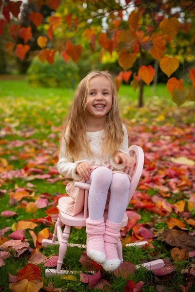 스웨터를 귀엽고 아이가 정원에 노란색 나뭇잎에 스커트와 양말을 흐릿하다 선택적으로 — 스톡 사진