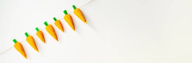 Easter white background with handmade felt carrots - orange and green. Place for text, ideal for flyer and advertisement. Flat lay