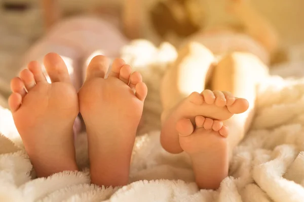 Sleep, rest, childhood, legs. Bare feet of a two children on a large bed. Selective focus - blurred background
