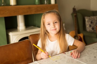 Easter and the child. Development, drawing. Cute cute girl with blond hair paints an Easter picture in a bright interior