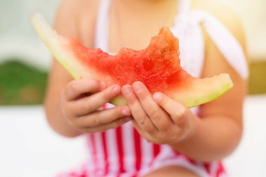 Yaz, karpuz, çocukluk. Çocuk ellerinde ısırılmış karpuz, çizgili kırmızı ve beyaz kıyafet, günbatımı, iyi ışıklandırma.