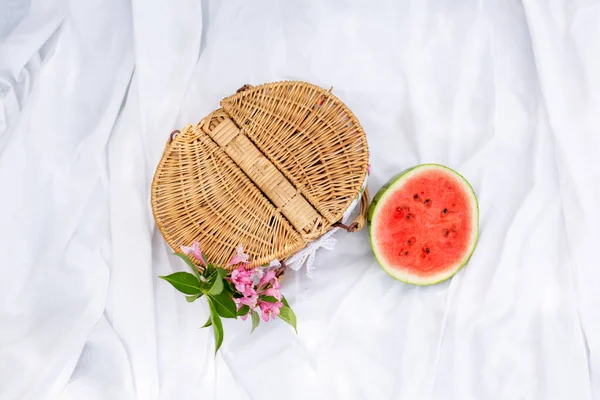 Picnic, snack, summer. Picnic basket and watermelon on a white blanket