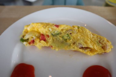 Fluffy breakfast omelet with gravy on white plate
