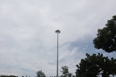 Düşük açılı mavi gökyüzü, kabarık beyaz bulutlar, güzel bir ağacın canlı yeşil yapraklarını gösteriyor..