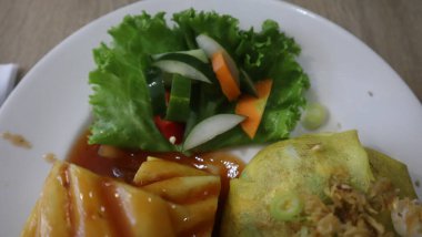 Beyaz bir tabakta servis edilen kızarmış patates pilavı, kızarmış tavuk parçaları ve sebzeler.