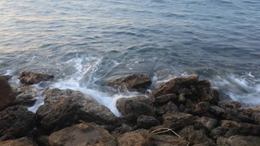 Deniz dalgaları kıyıdaki kayalara çarpıyor.