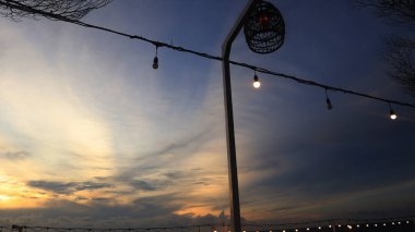 Güneşli havada mavi gökyüzünde elektrik ışıkları. Ev bahçelerini ve kafeleri ışıklandırmak için lambalar