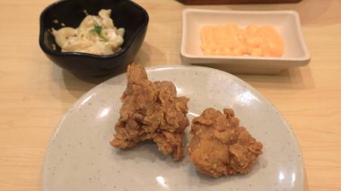 Ahşap bir masa ve beyaz tabakta servis edilen soslu ve mayonezli kızarmış tavuk fotoğrafı.