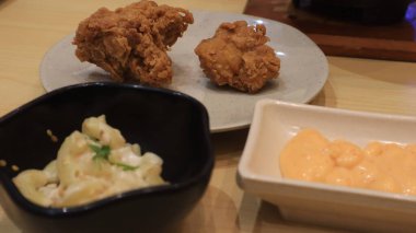 Ahşap bir masa ve beyaz tabakta servis edilen soslu ve mayonezli kızarmış tavuk fotoğrafı.