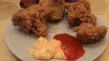 Ahşap bir masa ve beyaz tabakta servis edilen soslu ve mayonezli kızarmış tavuk fotoğrafı.