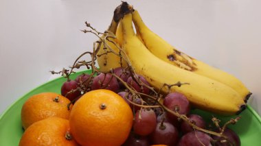 Beyaz arka planda muz üzümleri ve portakal meyvelerinin yakın plan fotoğrafı. İzole edilmiş