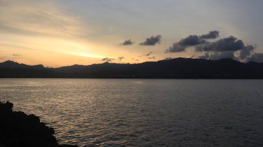 Endonezya 'da okyanus üzerinde dramatik bulutlarda düşük turuncu gün batımı