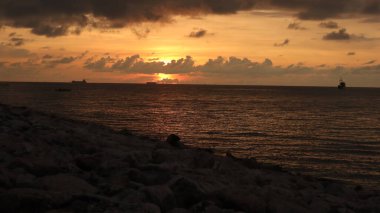 Endonezya 'da okyanus üzerinde dramatik bulutlarda düşük turuncu gün batımı