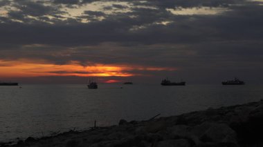 Endonezya 'da okyanus üzerinde dramatik bulutlarda düşük turuncu gün batımı