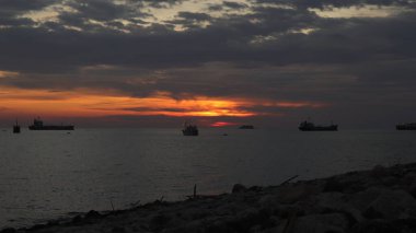 Endonezya 'da okyanus üzerinde dramatik bulutlarda düşük turuncu gün batımı