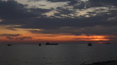 Endonezya 'da okyanus üzerinde dramatik bulutlarda düşük turuncu gün batımı