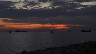 Endonezya 'da okyanus üzerinde dramatik bulutlarda düşük turuncu gün batımı