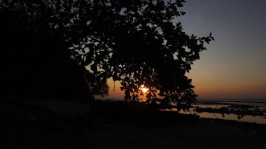 Endonezya 'da okyanus üzerinde dramatik bulutlarda düşük turuncu gün batımı