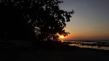 Endonezya 'da okyanus üzerinde dramatik bulutlarda düşük turuncu gün batımı