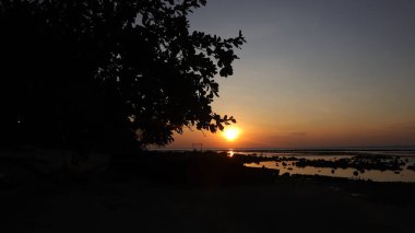 Endonezya 'da okyanus üzerinde dramatik bulutlarda düşük turuncu gün batımı